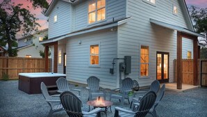 A two-story house with a patio area featuring outdoor seating and a fire pit.