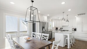 Una cocina moderna con armarios blancos, una isla central e iluminación colgante.