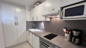 A modern kitchen with white cabinets, a built-in microwave, a coffee maker, and a dishwasher. - 150m from ski slopes, 8th floor, view ski slopes, balcony, tv, ski locker, 38m², Serre Chevalier (La Salle-les-Alpes)
