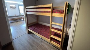 A bunk bed with red plaid bedding in a room with wooden flooring and a sloped ceiling. - 150m from ski slopes, 8th floor, view ski slopes, balcony, tv, ski locker, 38m², Serre Chevalier (La Salle-les-Alpes)