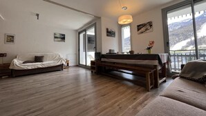 A spacious living room with a large window, a sofa, a coffee table, and a piano. - 150m from ski slopes, 8th floor, view ski slopes, balcony, tv, ski locker, 38m², Serre Chevalier (La Salle-les-Alpes)