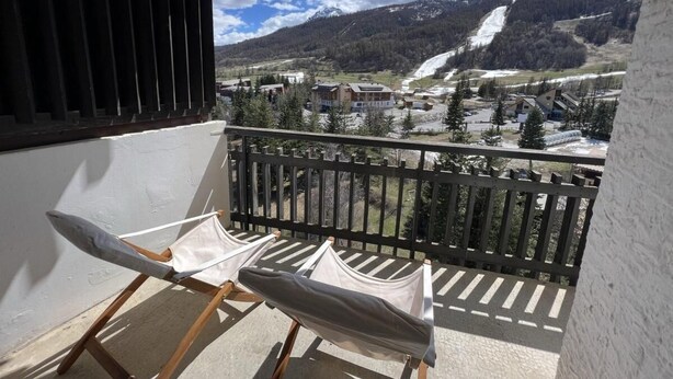 A balcony with a view of a mountainous landscape, including a waterfall and snow-covered slopes. - 150m from ski slopes, 8th floor, view ski slopes, balcony, tv, ski locker, 38m², Serre Chevalier (La Salle-les-Alpes)