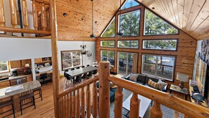A spacious cabin interior with a high ceiling, wooden walls, and large windows offering views of the outdoors. - Lakeside: 4 Kings, Room4Groups, Hot Tub, Dock, Firewood (Brainerd)