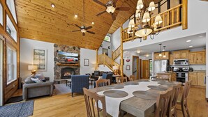 A spacious living area with a fireplace, wooden ceiling, and a dining table with chairs. - Lakeside: 4 Kings, Room4Groups, Hot Tub, Dock, Firewood (Brainerd)