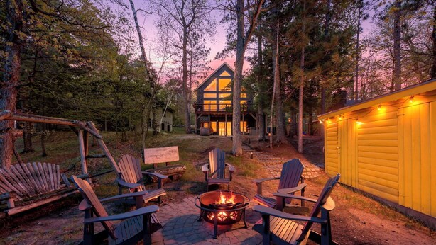 A cabin with a fire pit, outdoor seating, and a wooden deck. - Lakeside: 4 Kings, Room4Groups, Hot Tub, Dock, Firewood (Brainerd)