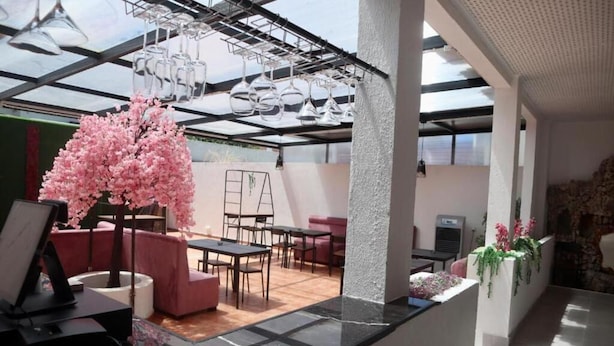 Un intérieur moderne avec un plafond en verre, un cerisier en fleurs aux teintes roses et un espace détente comprenant des canapés et des tables.