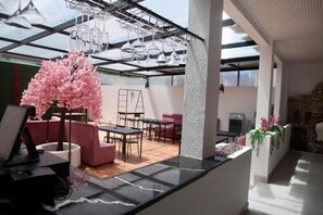 A modern interior with a glass ceiling, a pink cherry blossom tree, and a seating area with sofas and tables.
