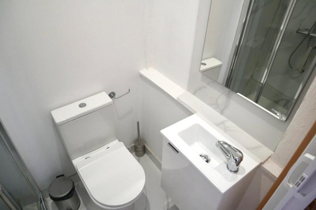 A compact bathroom with a toilet, a sink, and a glass shower enclosure.