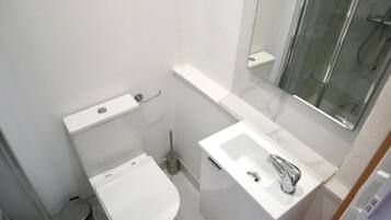 Ein kleines Badezimmer mit Toilette, Waschbecken und einer Duschkabine aus Glas.