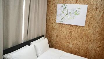Ein Hotelzimmer mit Bett, weißen Bettwäsche, einer Holzwand und einem gerahmten Blumenbild.