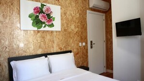 Une chambre d’hôtel avec un lit, un téléviseur fixé au mur et une porte.