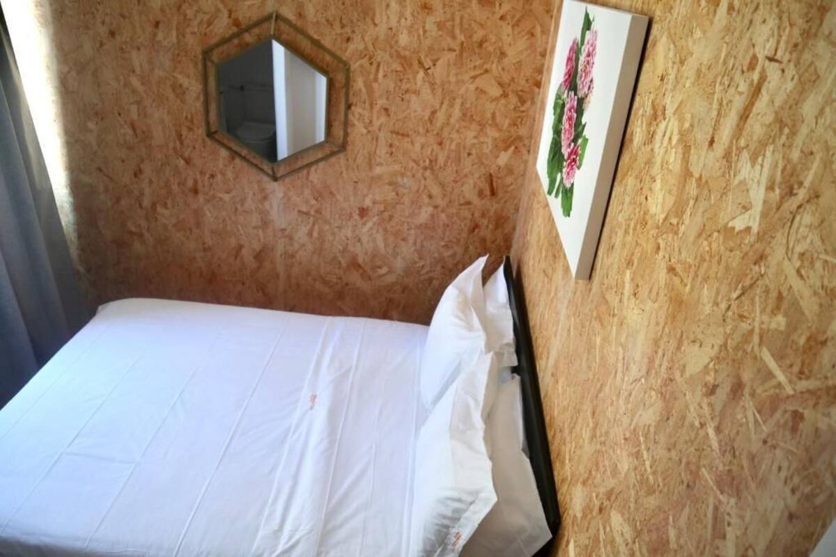 Un lit simple avec une literie blanche, dans une pièce aux murs en bois.