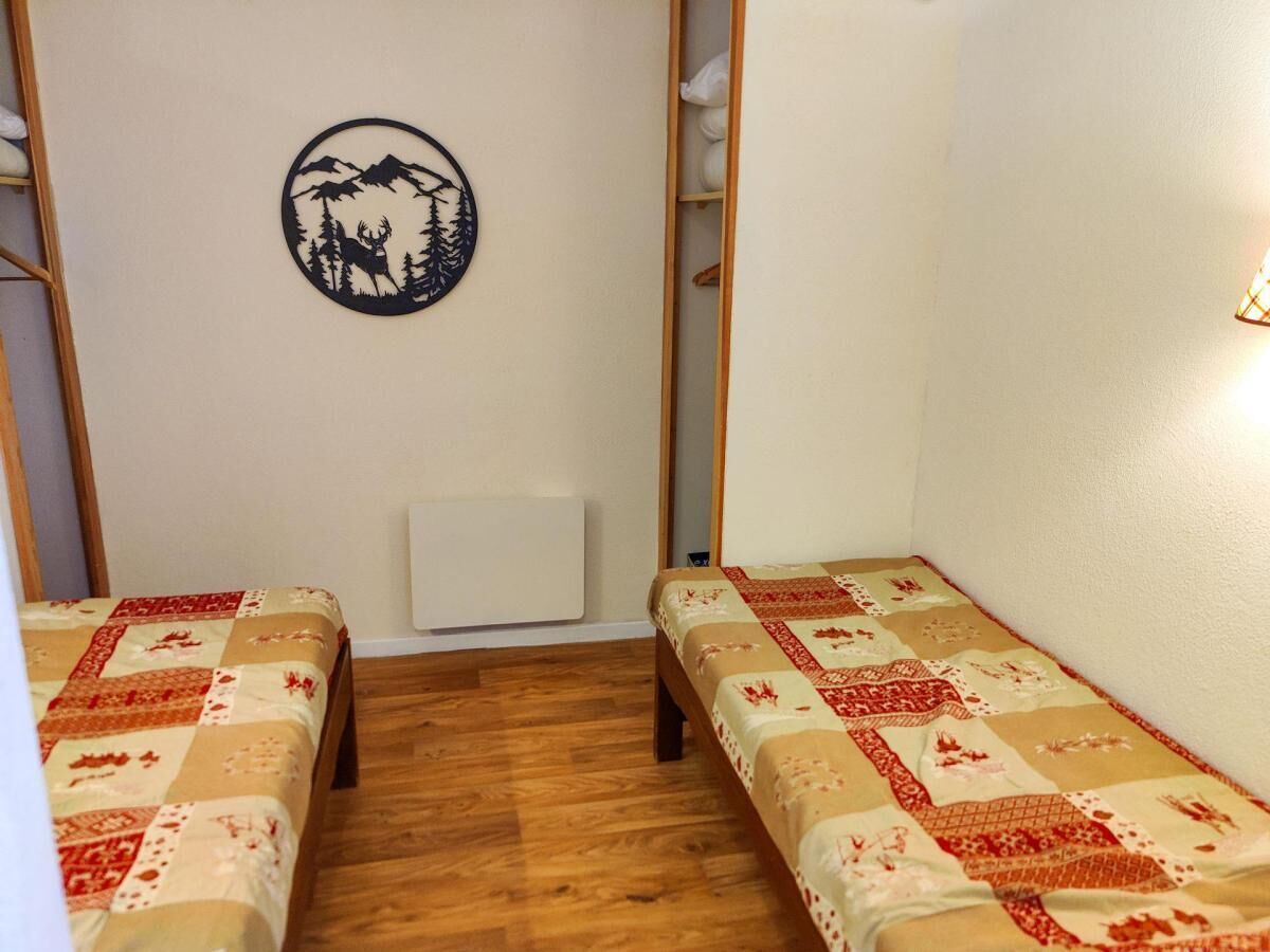 A small, cozy room with two single beds, a radiator, and a wall decoration.