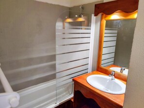 Une salle de bain avec une douche à parois de verre, un lavabo blanc et un miroir.