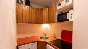 A compact kitchen with wooden cabinets, a sink, a dishwasher, and a microwave. - 50m from ski slopes, 1st floor, view street, fitness, swimming pool, sauna, balcony, tv, ski locker (Les Orres)