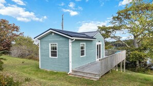 Una piccola casa a un piano con una veranda in legno e un piccolo portico.