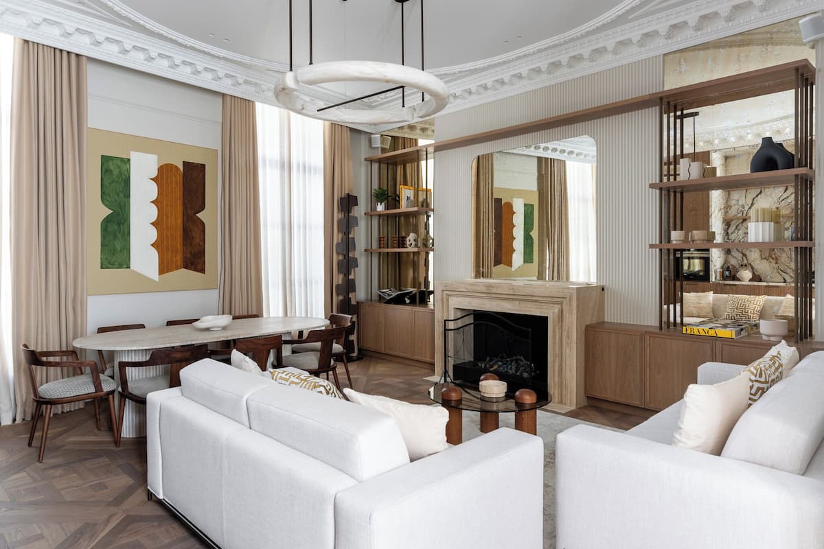 A spacious living room with a fireplace, a dining area, and a large mirror.