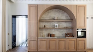 A kitchen with wooden cabinets, marble countertops, and a built-in oven. - HIGHSTAY - Luxury Serviced Apartments - Le Marais (Paris)