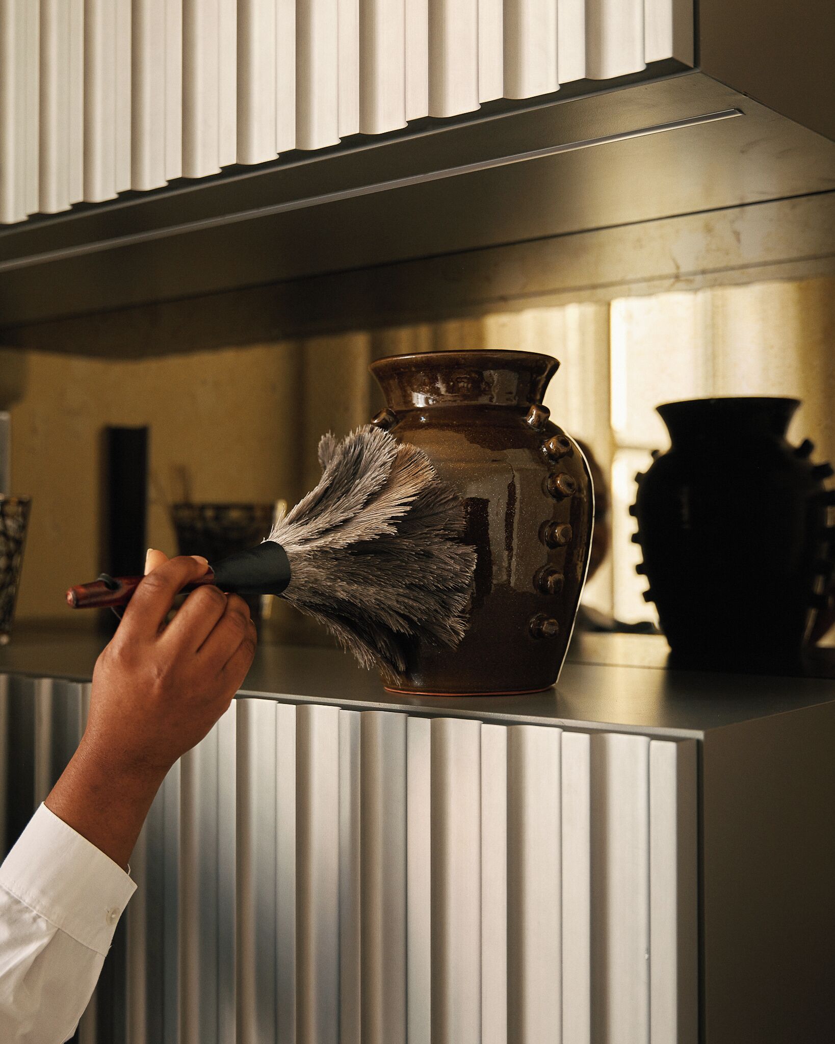 A hand holding a brush cleaning a metallic surface.