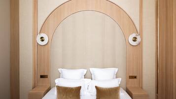 Una habitación de hotel con una cama grande, dos mesitas de noche y un cabecero de madera con un arco curvo.