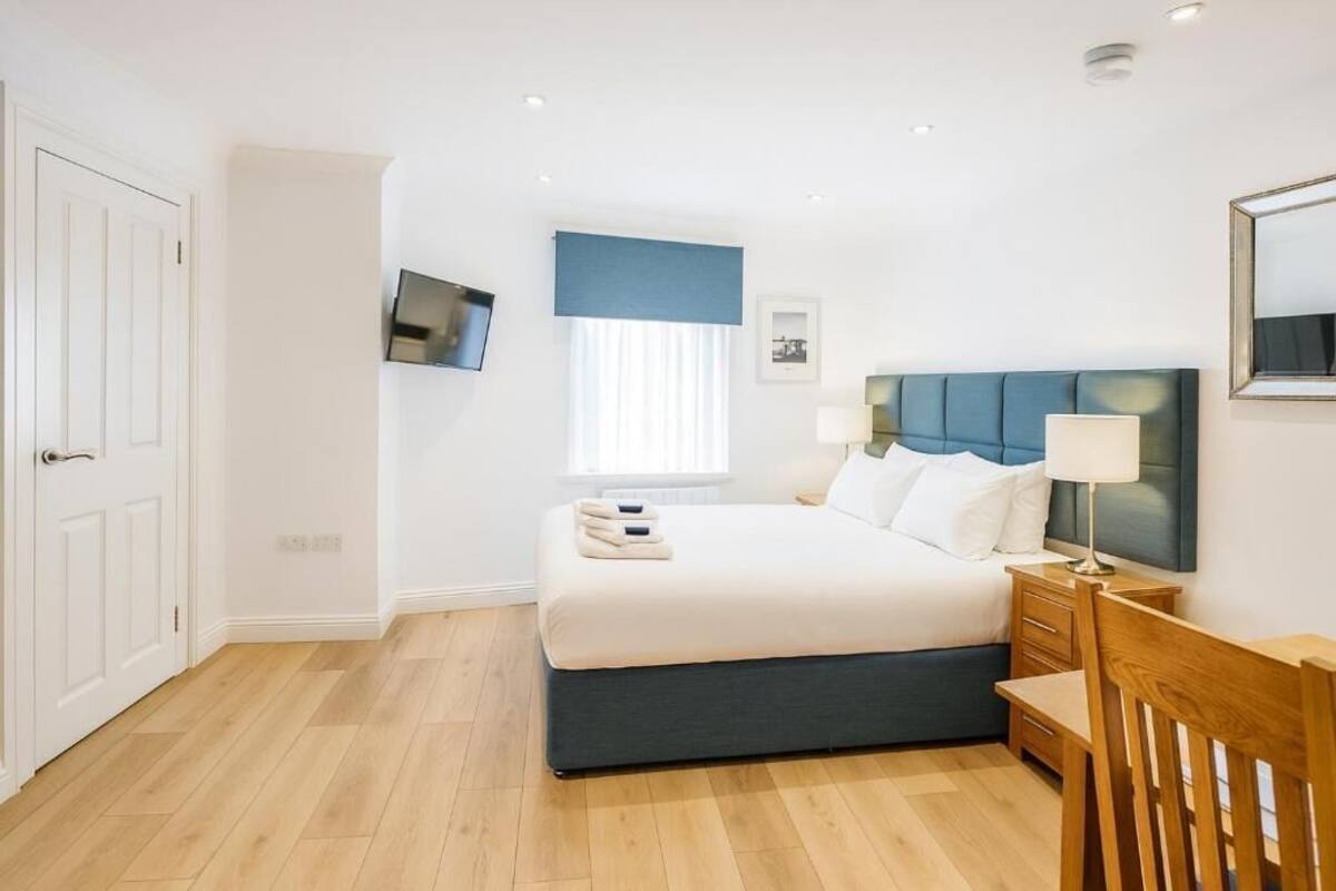 A hotel room with a bed, bedside tables, a TV, and a window with curtains.