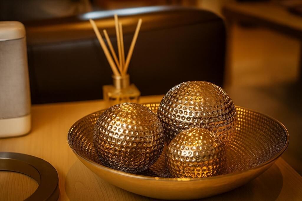 Un bol contenant trois objets sphériques à la texture variée, posé sur une table en bois.
