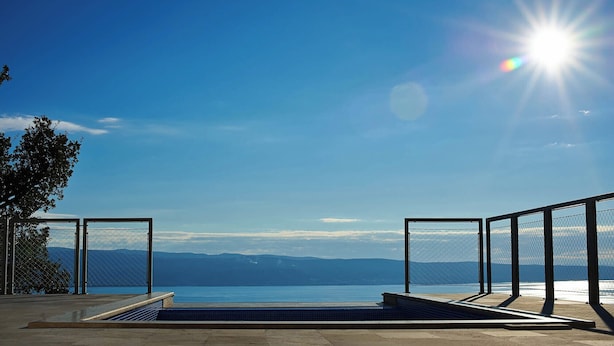 Piscina infinita com vista para o mar e montanhas.