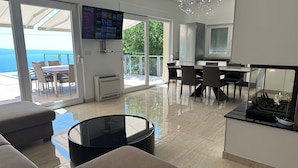 Uma sala de estar moderna com uma mesa de jantar de vidro, uma mesa de centro preta e um sofá.