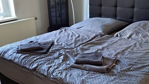 A bedroom with a bed, a dark wooden headboard, a wall clock, and a radiator.
