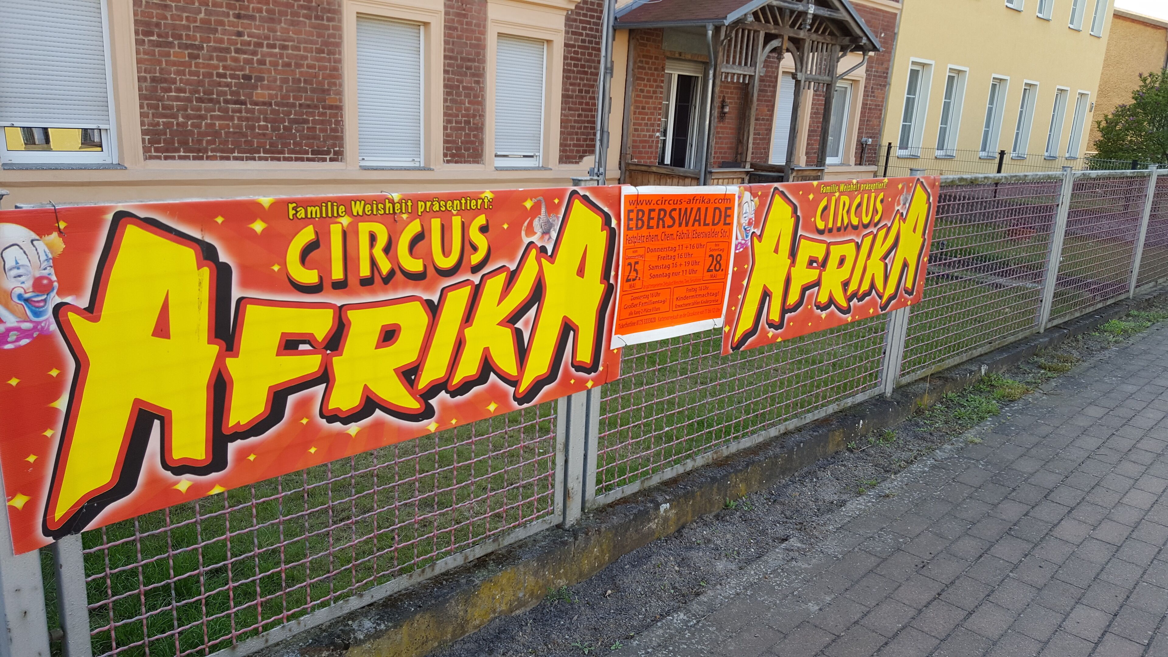 A fence with multiple signs advertising a circus.