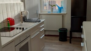 A compact kitchen with white cabinets, a built-in oven, a sink, and a window with a view of the outside.