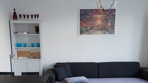A modern living room with a dark sofa, a red coffee table, and a dining area with chairs and a table.