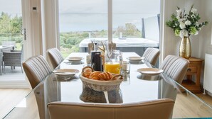 Un comedor con una mesa de vidrio, sillas de cuero y vistas al exterior.