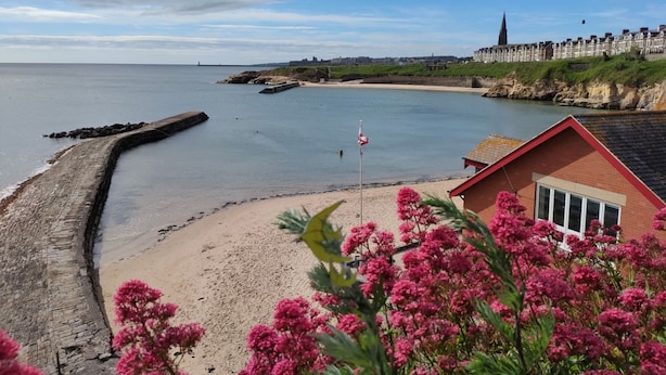 A coastal scene with a sandy beach, a stone sea wall, and a row of terraced houses in the background. - Chaff House – Dog‑Friendly Family Cottage on Burradon Farm near coast (Cramlington)