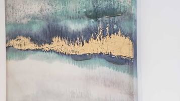 Una pintura con formas y colores abstractos, colgada en una pared blanca.