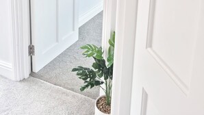Une porte blanche avec une plaque portant le nom « Hylands », une plante en pot et un miroir accroché au mur.