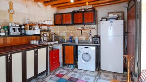 A compact kitchen with wooden cabinets, a washing machine, and a refrigerator. - Lütfü Bey Konağı (Gaziantep)
