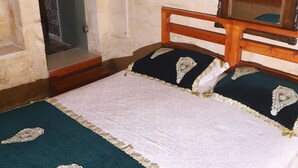 A bedroom with a wooden bed, a mirror, and a door to a bathroom. - Lütfü Bey Konağı (Gaziantep)