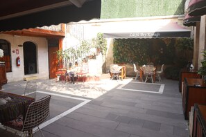 An outdoor seating area with tables and chairs, surrounded by potted plants and a decorative wall. - Lütfü Bey Konağı (Gaziantep)