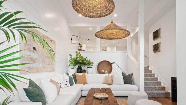 A modern living room with a white sofa, a wooden coffee table, and a large plant.