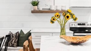A modern kitchen with white cabinetry, a wooden dining table, and a large island with a white marble countertop.