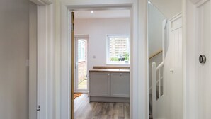 Un pasillo estrecho que lleva a una cocina con ventana y puerta.