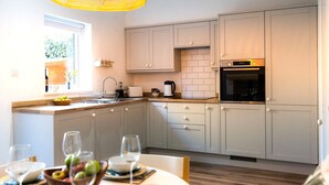 Una cocina moderna con armarios de tonos claros, horno empotrado y ventana que proporciona luz natural.