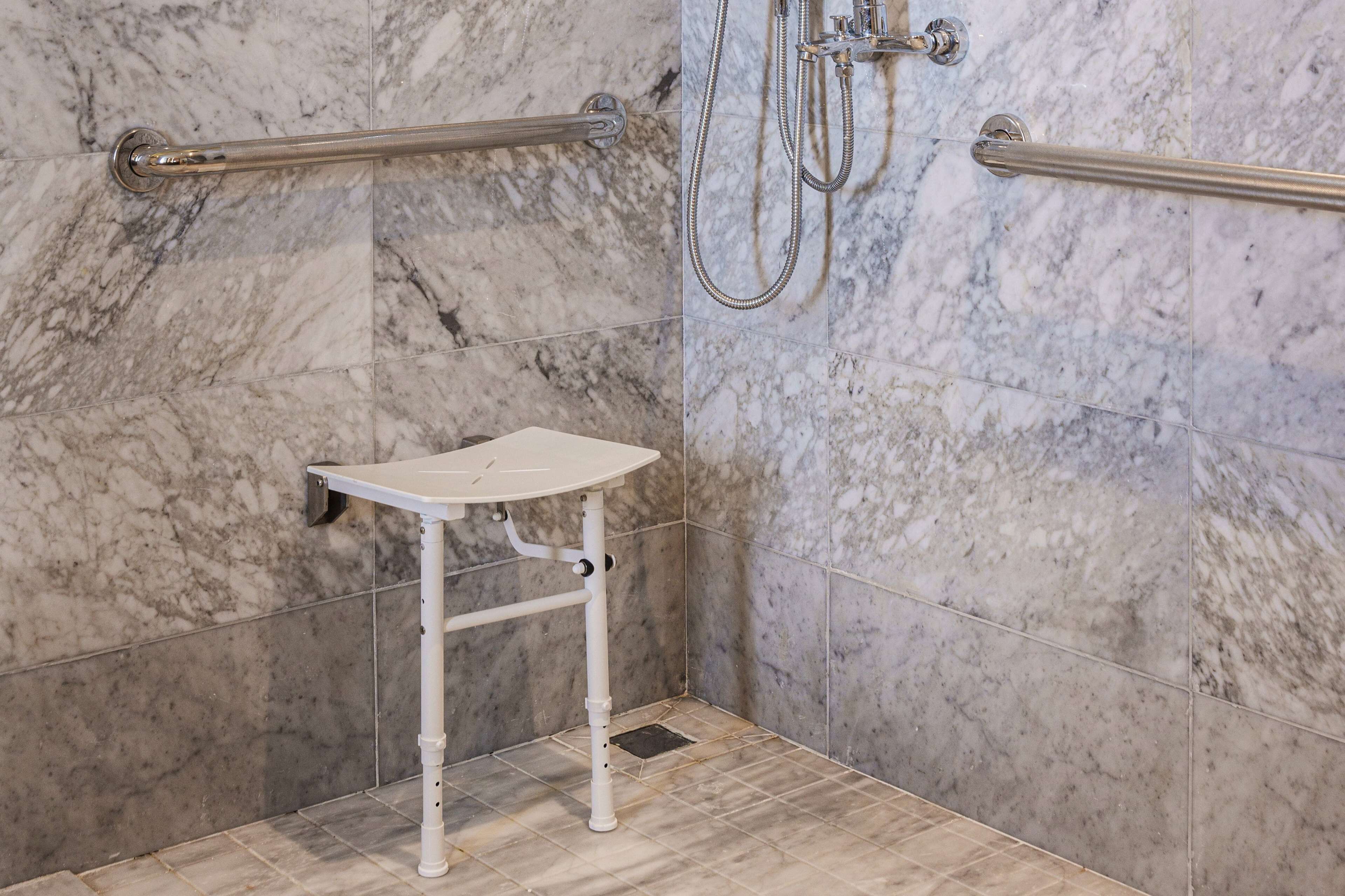 A bathroom with marble walls, a white sink, and a grab bar.