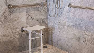 A bathroom with marble walls, a white sink, and a grab bar.