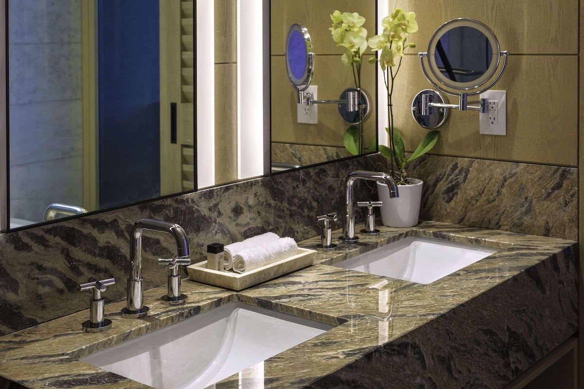 A bathroom with two sinks, a large mirror, and a potted orchid.