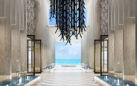 A spacious lobby with a view of the ocean, marble flooring, and modern lighting fixtures.