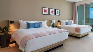 A hotel room with two beds, a large window, and a potted plant.