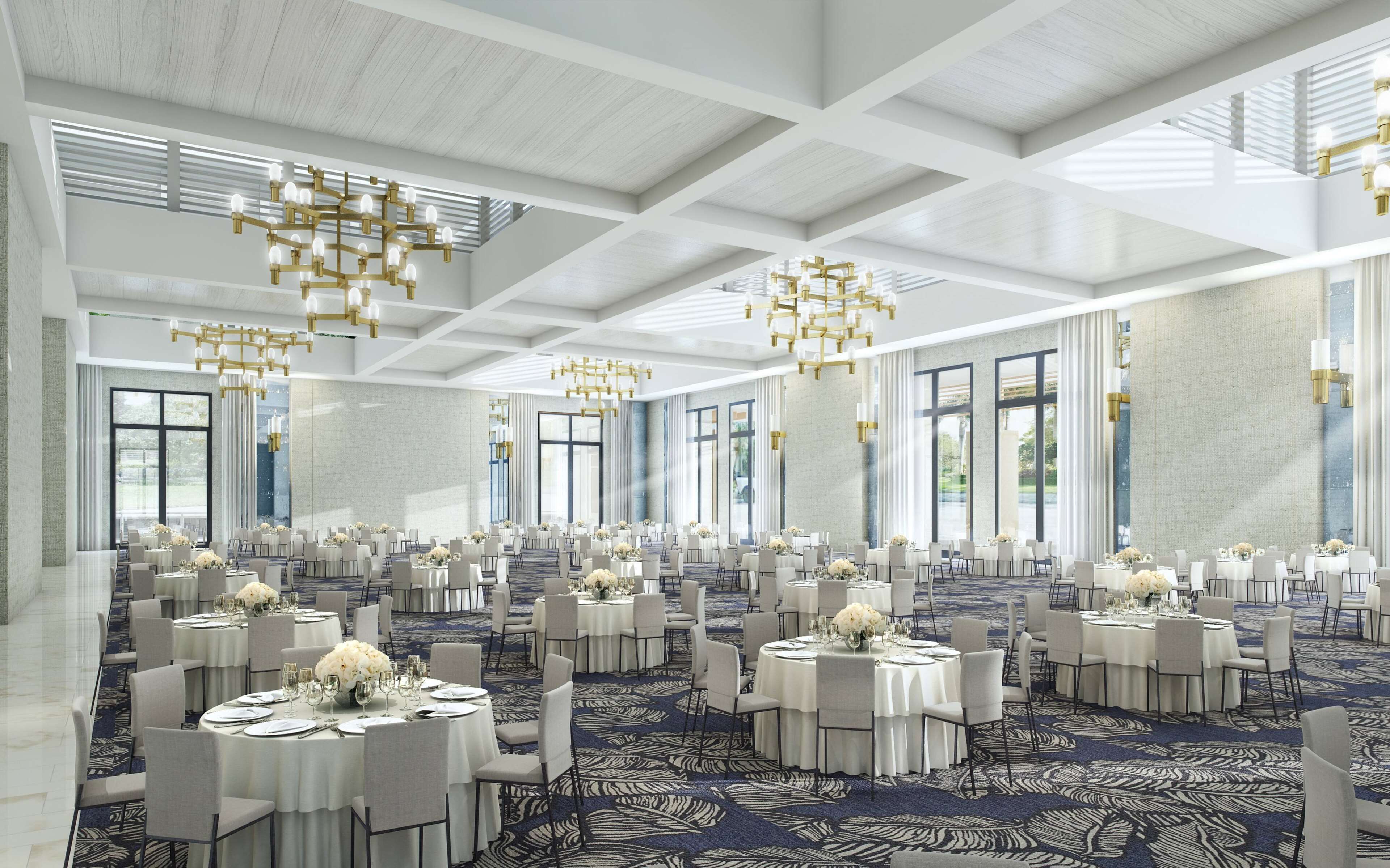 Un amplio salón de banquetes con mesas redondas, manteles blancos y candelabros dorados.