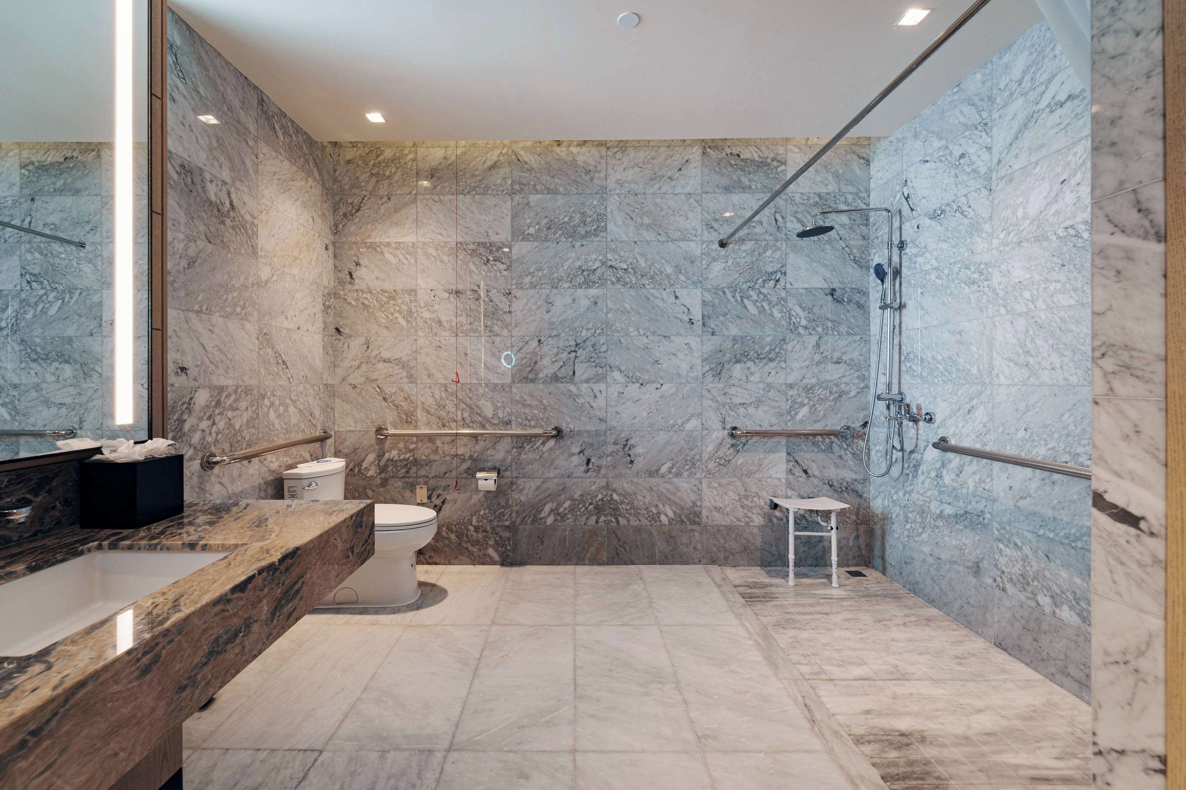 Une salle de bain moderne avec une douche en marbre, une baignoire et des toilettes.